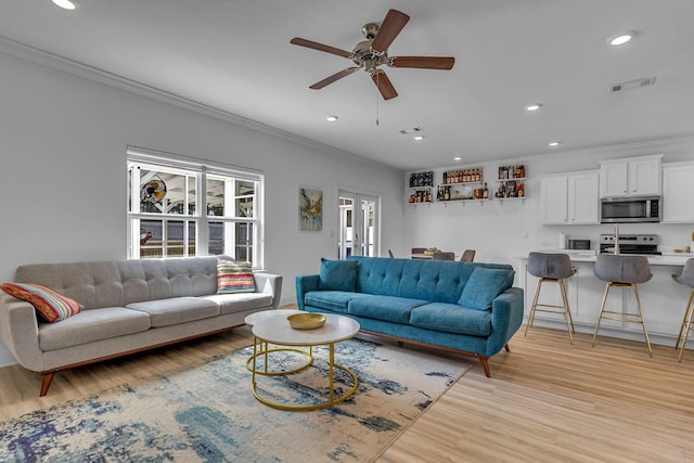 living room with ornamental molding, recessed lighting, visible vents, and light wood finished floors