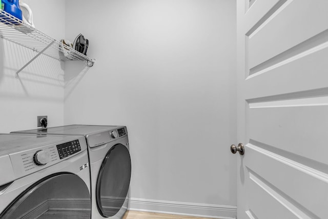 laundry room featuring laundry area, washer and clothes dryer, light wood-style flooring, and baseboards