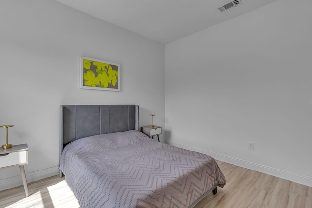 bedroom featuring visible vents, baseboards, and wood finished floors