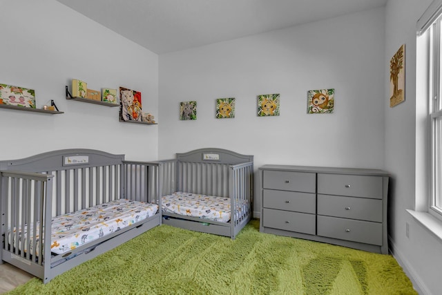 carpeted bedroom featuring a crib and baseboards