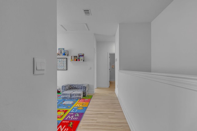 rec room featuring light wood-style flooring, attic access, visible vents, and baseboards