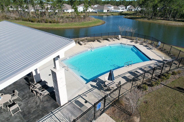 community pool with a patio, a water view, fence, and a residential view