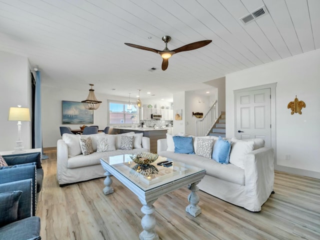 living room with light wood finished floors, visible vents, stairway, ceiling fan, and baseboards