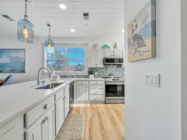 kitchen with stainless steel appliances, visible vents, a sink, and hanging light fixtures