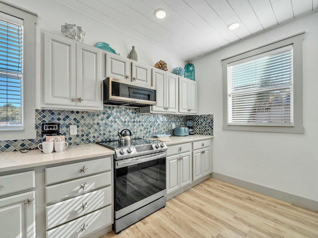 kitchen featuring white cabinets, decorative backsplash, stainless steel appliances, light countertops, and light wood-type flooring