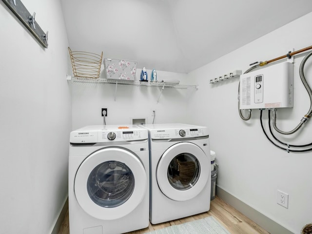 clothes washing area with laundry area, light wood finished floors, washing machine and dryer, and baseboards