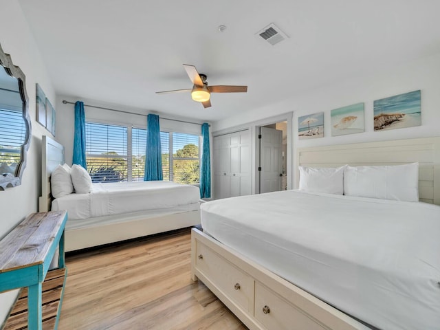 bedroom with light wood-style floors, a closet, visible vents, and a ceiling fan