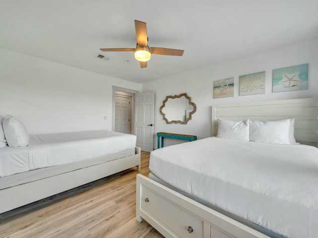 bedroom with light wood finished floors, ceiling fan, and visible vents