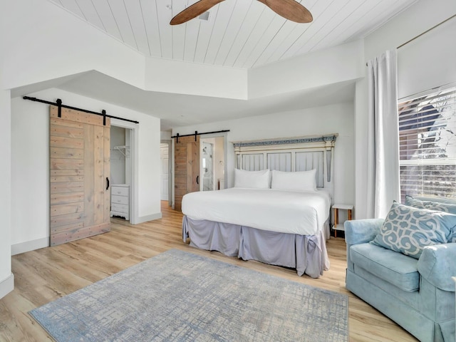 bedroom featuring a tray ceiling, a barn door, wooden ceiling, and wood finished floors