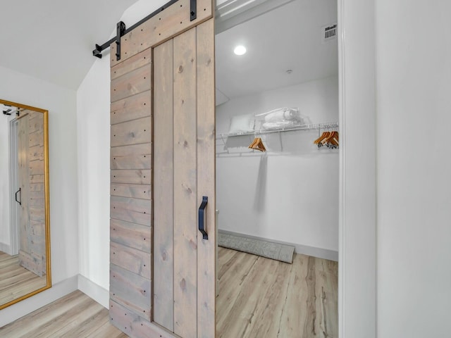 walk in closet featuring a barn door, visible vents, and wood finished floors