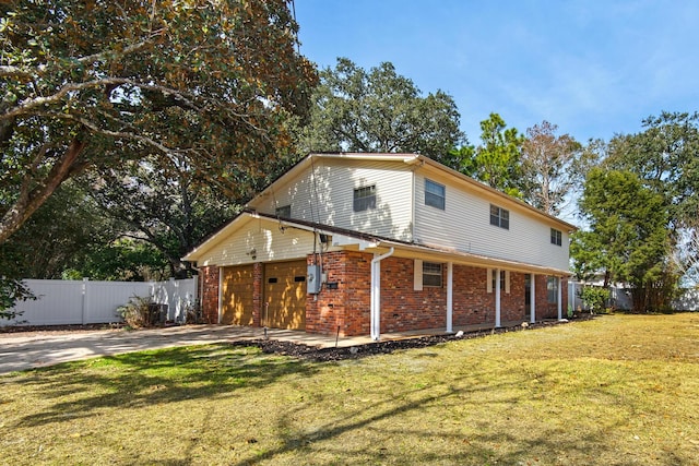 view of home's exterior featuring concrete driveway, brick siding, a lawn, and fence