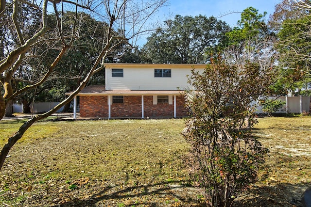 rear view of property featuring fence, a lawn, and brick siding