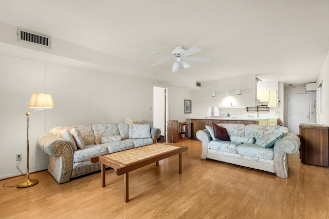 living room featuring ceiling fan, light wood-type flooring, and visible vents