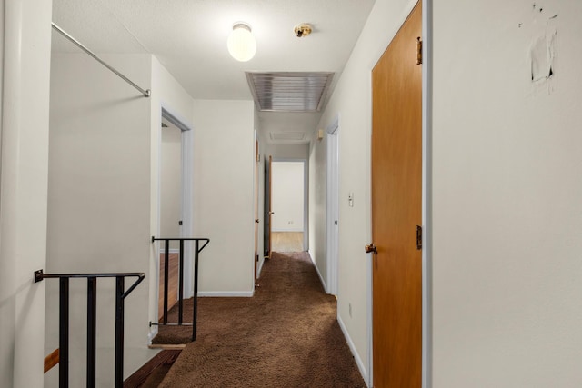 hallway featuring carpet, baseboards, and an upstairs landing