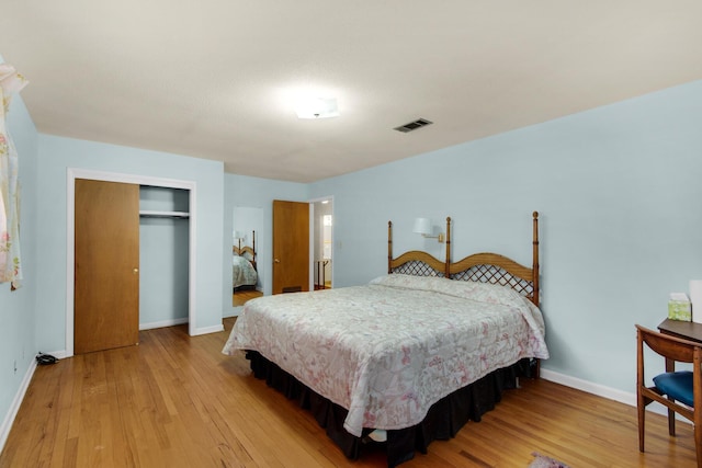 bedroom with light wood-style floors, baseboards, visible vents, and a closet