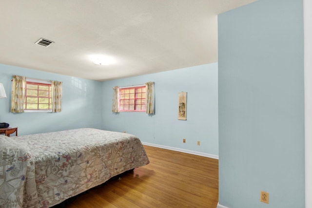 bedroom with visible vents, baseboards, and wood finished floors