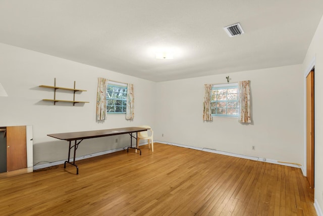 empty room featuring a healthy amount of sunlight, hardwood / wood-style flooring, baseboards, and visible vents