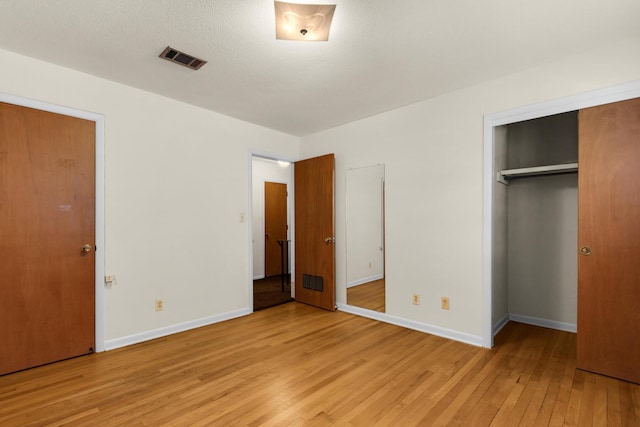 unfurnished bedroom featuring light wood finished floors, baseboards, visible vents, and a closet