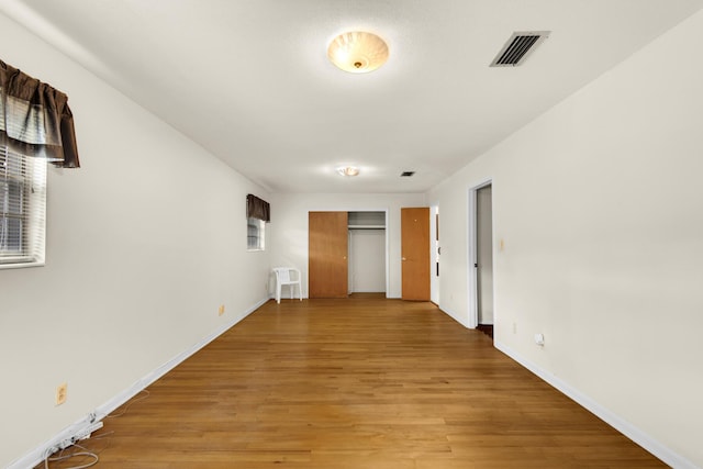 unfurnished bedroom featuring baseboards, a closet, visible vents, and light wood-style floors