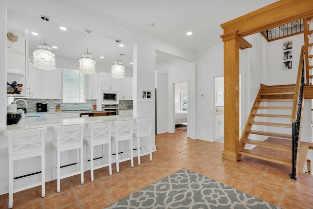 kitchen featuring a breakfast bar, a sink, stainless steel oven, built in microwave, and tasteful backsplash