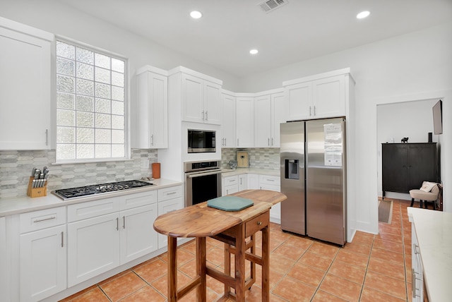 kitchen with light tile patterned floors, stainless steel appliances, tasteful backsplash, light countertops, and white cabinetry