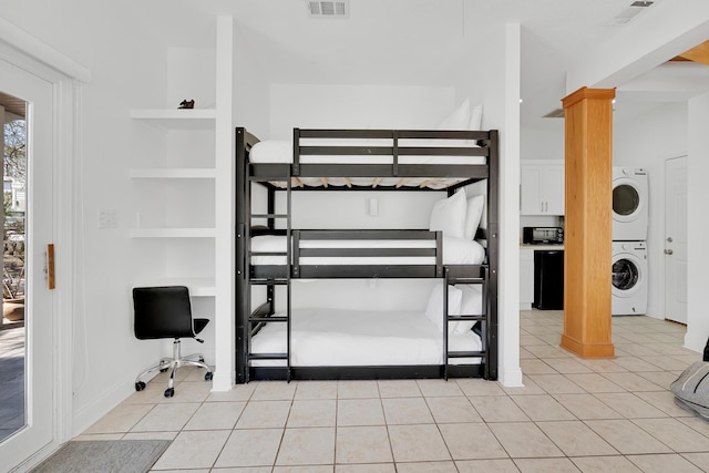 unfurnished bedroom with stacked washer / dryer, visible vents, decorative columns, and light tile patterned floors