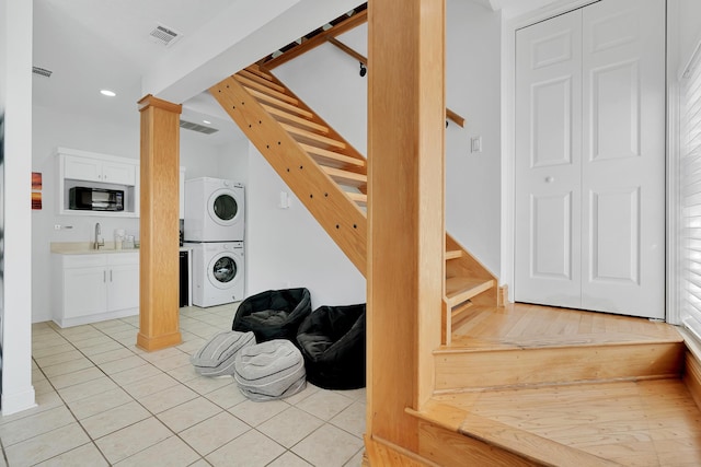 stairs with tile patterned flooring, decorative columns, visible vents, and stacked washer / dryer