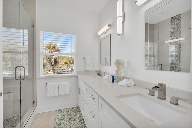 full bath featuring a stall shower, a sink, baseboards, and double vanity