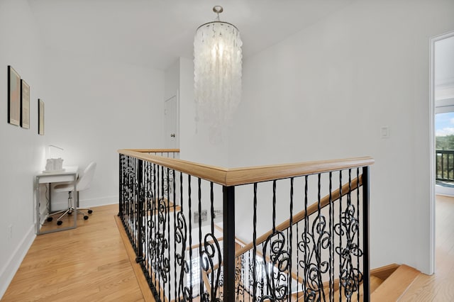 hall with a chandelier, light wood finished floors, an upstairs landing, and baseboards