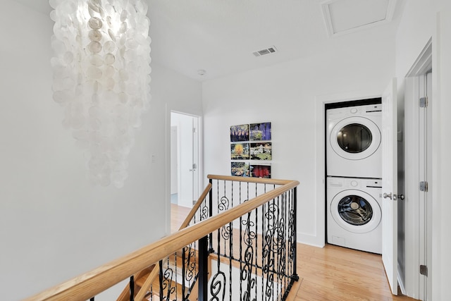 laundry room with laundry area, stacked washing maching and dryer, visible vents, and light wood-style floors