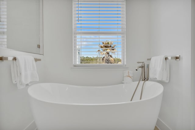 bathroom with a soaking tub and baseboards