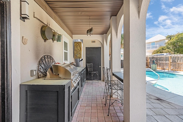 view of patio / terrace featuring a fenced in pool, grilling area, area for grilling, fence, and outdoor wet bar