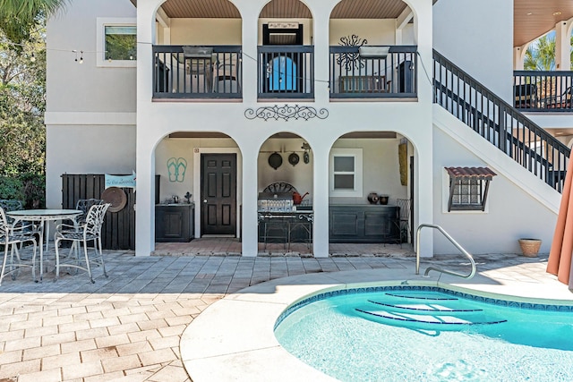 back of property with stucco siding, outdoor dining space, an outdoor pool, and a patio