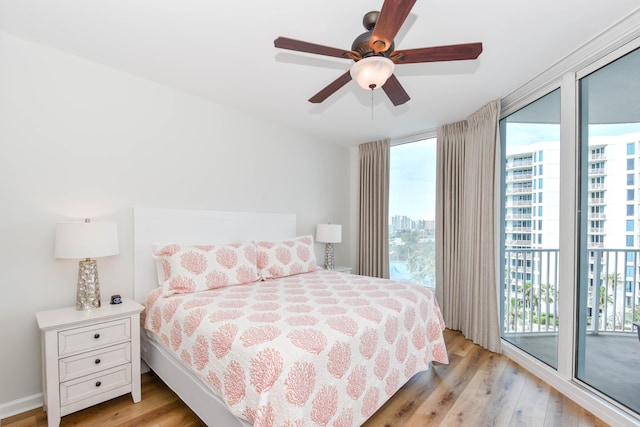 bedroom featuring light wood-type flooring, access to outside, floor to ceiling windows, and a city view