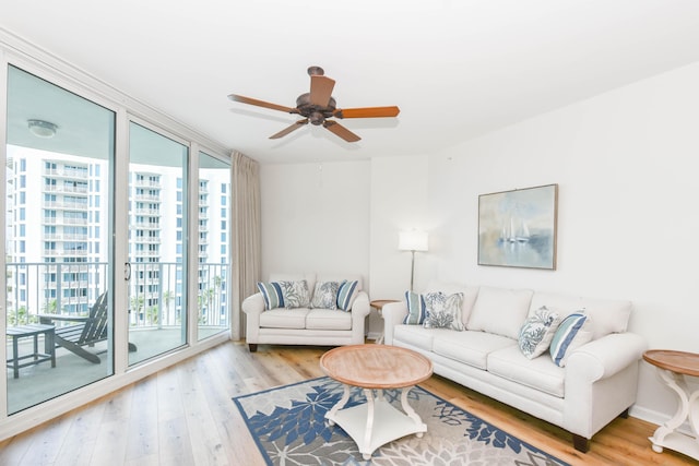 living area with ceiling fan, expansive windows, and wood finished floors