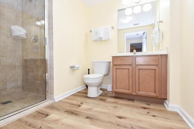 bathroom with toilet, a shower stall, baseboards, and wood finished floors