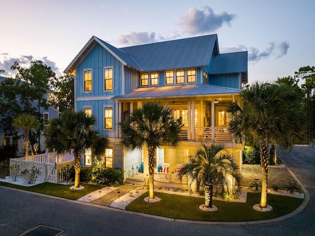 view of front of property with board and batten siding, a front yard, fence, and a ceiling fan