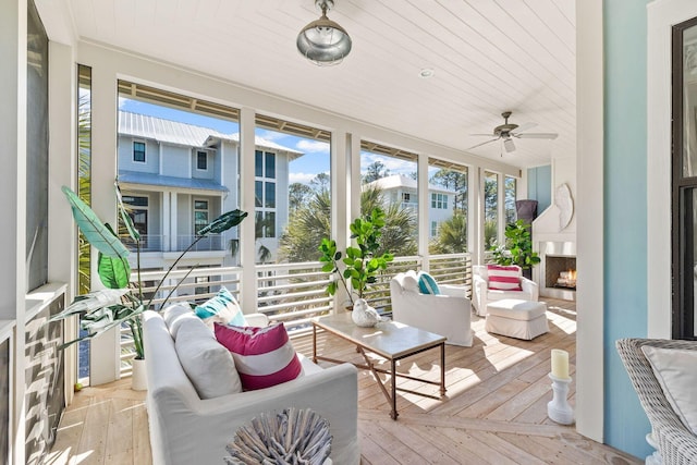 sunroom / solarium with a ceiling fan and a large fireplace