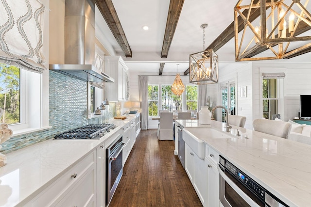 kitchen featuring tasteful backsplash, white cabinets, dark wood finished floors, stainless steel appliances, and wall chimney range hood