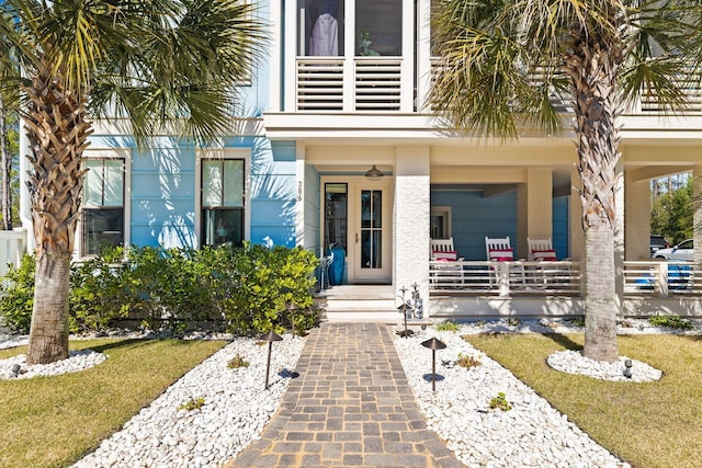 view of exterior entry with a porch and a balcony