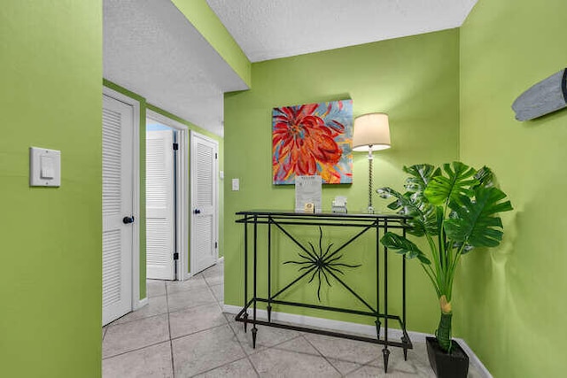 hallway with tile patterned flooring, baseboards, and a textured ceiling