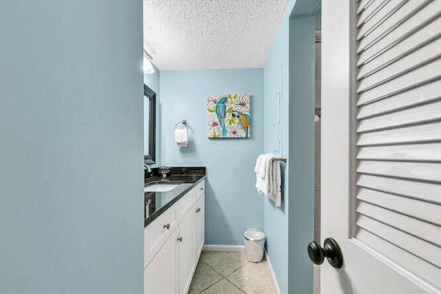 bathroom featuring tile patterned flooring, baseboards, a textured ceiling, and vanity