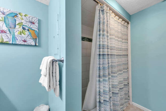 full bath with baseboards, a textured ceiling, and a shower with shower curtain