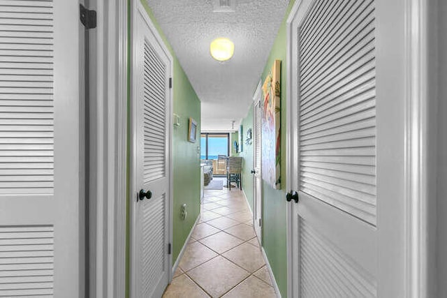 hallway with light tile patterned floors and a textured ceiling