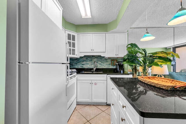 kitchen featuring white appliances, light tile patterned floors, a sink, white cabinetry, and backsplash