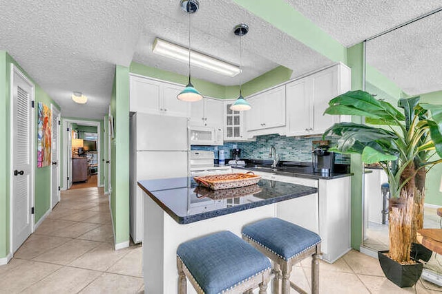 kitchen featuring white appliances, light tile patterned floors, a sink, white cabinetry, and backsplash