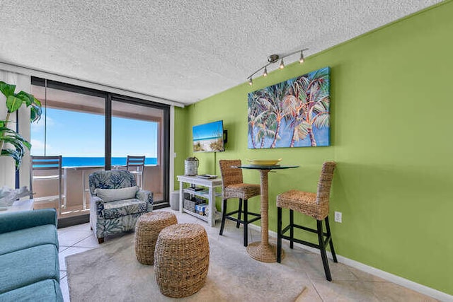 tiled living room with a textured ceiling, rail lighting, and baseboards