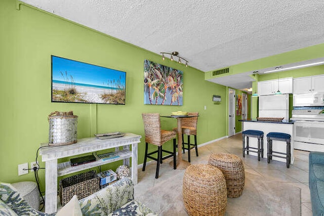 dining space featuring a textured ceiling, visible vents, and baseboards