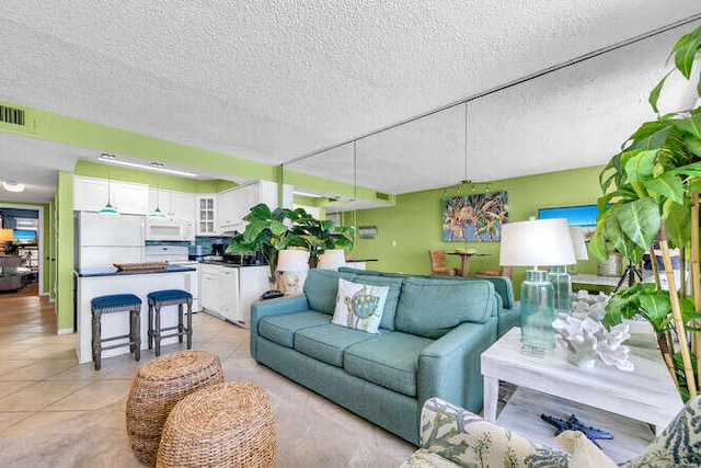 living room featuring light tile patterned floors, visible vents, and a textured ceiling