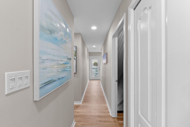 corridor with recessed lighting, light wood-type flooring, a baseboard radiator, and baseboards